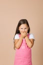 Portrait photo of female kid closing mouth with hands not talk with others with shining eyes and sullen look looking at