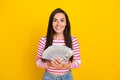 Portrait photo of young attractive cute smiling woman hold stack money dollars win bet isolated on yellow color Royalty Free Stock Photo