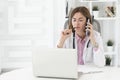 Portrait photo of young female doctor in white medical gown sitting and working on laptop in the office of the modern clinic Royalty Free Stock Photo