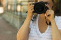 Portrait of a photographer covering her face with the camera.. Photographer woman girl is holding dslr camera taking photographs Royalty Free Stock Photo