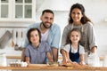 Portrait picture of happy young couple with children cooking dinner.