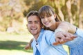 Portrait, piggy back and couple in a park, love and happiness with marriage and romance. Face, man carrying woman or