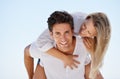 Portrait, piggy back and happy couple on blue sky for date, outdoor bonding and holiday love. Romance, man and woman in