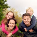 Portrait, piggyback and happy family outdoor in nature for holiday, vacation or travel in woods. Face, mother and father