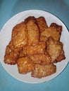 Portrait of a pile of food called fried tempe, a traditional Indonesian food. Fried fermented soybean meal served on a white plate Royalty Free Stock Photo