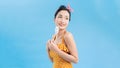 Portrait of pin-up woman 20s in vintage polka dot dress smiling while holding and eating colorful lollipop  over blue Royalty Free Stock Photo