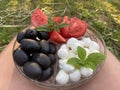 Portrait of a plate with large black olives lying on a glass plate next to red tomatoes and white mozzarella balls Royalty Free Stock Photo