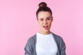 Portrait of playful brunette teenage girl winking at camera, looking charming and coquettish. isolated on pink background