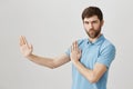 Portrait of playful charming european man who acts like ninja or karate fighter, standing half-turned in defence pose