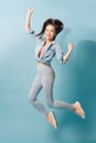 Portrait of playful crazy girl jumping in the air looking at camera enjoying weekend having perfect mood on light blue background