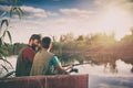 Handsome father and son sitting in boat on lake while enjoying fishing together