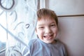 Portrait of playful laughting little boy at the window