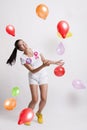 Portrait of playful young woman with multicolored balloons celebrating her birthday against white background Royalty Free Stock Photo