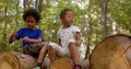 Portrait of playing curly emotionally close children on the logs in a city park.