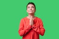 Portrait of pleading young woman with bun hairstyle, big earrings and in red blouse. indoor studio shot isolated on green Royalty Free Stock Photo