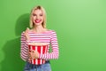 Portrait of pleasant cheerful girlish woman wear striped stylish shirt hold pop corn basket at cinema isolated on green