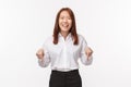 Portrait of pleasant happy asian lady in white shirt and skirt, laughing and smiling carefree, pointing fingers down to Royalty Free Stock Photo