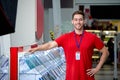 Portrait of pleasant smiling consultant in red uniform posing by shopfront Royalty Free Stock Photo