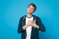 Portrait of pleasant smiling young man in casual clothes holding palms crossed on heart, chest isolated on blue Royalty Free Stock Photo