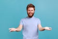 Man in blue T-shirt sharing opening hands looking at camera with kind smile, greeting and regaling.