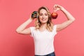 Portrait of pleased blond woman 20s wearing casual t-shirt holding sweet donut and fresh healthy apple Royalty Free Stock Photo