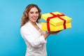 Portrait of pleased charming woman unpacking big present and cute smiling at camera. blue background Royalty Free Stock Photo