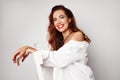 Pleased young brown-eyed curly brunette woman looking at camera with charming smile while over white background.