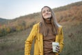 Portrait of pleasing happy girl in yellow jacket on mountainous area background. Young woman walks in nature, autumn day Royalty Free Stock Photo