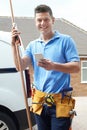 Portrait Of Plumber With Van Texting On Mobile Phone Outside House