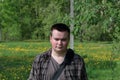 Portrait of a plump young man. On a spring meadow with bright green young grass and trees Royalty Free Stock Photo