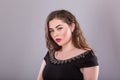 Portrait of a plus size female model posing in black dress over grey background. Royalty Free Stock Photo
