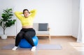 Portrait plus size woman doing exercise with fitness ball in home gym. Overweight woman sitting on a pilates ball and Stretching Royalty Free Stock Photo