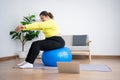 Portrait plus size woman doing exercise with fitness ball in home gym. Overweight woman sitting on a pilates ball and Stretching Royalty Free Stock Photo