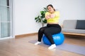 Portrait plus size woman doing exercise with fitness ball in home gym. Overweight woman sitting on a pilates ball and Stretching Royalty Free Stock Photo