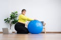 Portrait plus size woman doing exercise with fitness ball in home gym. Overweight woman sitting on a pilates ball and Stretching Royalty Free Stock Photo