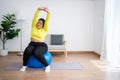 Portrait plus size woman doing exercise with fitness ball in home gym. Overweight woman sitting on a pilates ball and Stretching Royalty Free Stock Photo