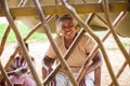 Portrait of a poor, elderly Indian woman behind a fence in the form of a lattice