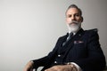 Portrait of positive bearded gentleman wearing trendy suit over empty gray background. Copy Paste space. Studio shot