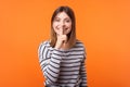 Portrait of positive beautiful woman with brown hair in long sleeve striped shirt. indoor studio shot isolated on orange