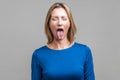 Portrait of positive carefree woman demonstrating tongue. indoor studio shot isolated on gray background Royalty Free Stock Photo