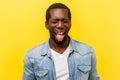 Portrait of positive carefree young man showing out his tongue. indoor studio shot isolated on yellow background Royalty Free Stock Photo