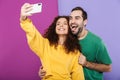 Portrait of positive caucasian couple in colorful clothing having fun while taking selfie photo on cellphone Royalty Free Stock Photo