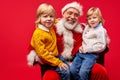 Portrait of positive caucasian santa and kids sitting on his knees Royalty Free Stock Photo