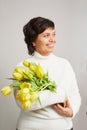 Portrait of positive charming cheerful old woman granny receive bunch of tulips smell close eyes enjoy 8-march celebration. Royalty Free Stock Photo