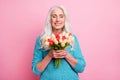 Portrait of positive charming cheerful old woman granny receive bunch of tulips smell close eyes enjoy 8-march