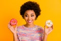 Portrait of positive cheerful afro american girl hold two yummy donuts look want eat sweet snack wear casual style