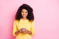 Portrait of positive cheerful black lady feel interested use her cell phone read feednews in social network account wear Royalty Free Stock Photo