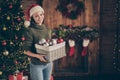 Portrait of positive cheerful dreamy girl in santa claus hat knitted jumper hold box with many christmas toys want Royalty Free Stock Photo