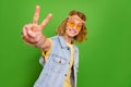 Portrait of positive cheerful hippy person hand fingers demonstrate v-sign isolated on green color background