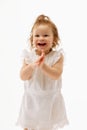 Portrait of of positive, cheerful little toddler, laughing and clapping of joy and happiness baby girl in cute dress Royalty Free Stock Photo